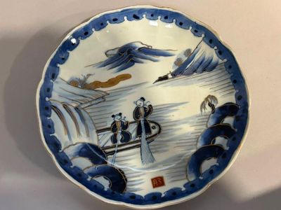 une assiette bleue et blanche sur laquelle figurent des personnes à bord d'un bateau