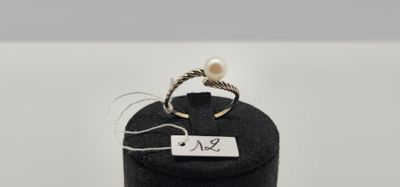 un gros plan d'une bague dans une boîte noire posée sur une surface blanche