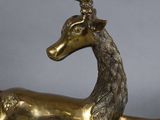 bronze sculpture of a deer laying down on a grey surface