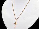 un collier en or orné d'une croix, posé sur le cou d'un mannequin