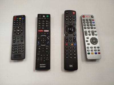 quatre télécommandes sont alignées sur une surface blanche