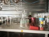 bottles and glasses on a shelf with a chandelier in the background