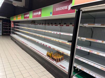 de nombreuses étagères vides dans un magasin, sur lesquelles sont posées des boissons
