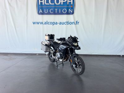 une moto noire garée devant un panneau bleu et blanc