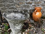 two vases sitting next to each other near a stone wall