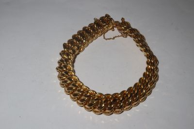 a close up of a gold chain bracelet on a white surface