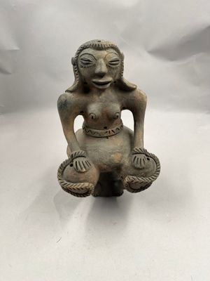 un gros plan sur la statue d'une femme assise sur une surface blanche