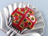 a silver and red brooch with a red cross on it