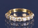 gros plan d'une bague en or avec des diamants sur une surface noire