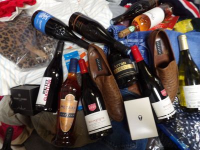 a pile of bottles of wine and shoes on a bed