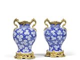 paire de vases bleus et blancs avec des anses dorées, posés sur des socles
