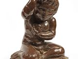 statue représentant un garçon agenouillé sur un rocher, les mains posées sur ses genoux
