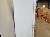 a white refrigerator sitting in a warehouse next to a pile of boxes