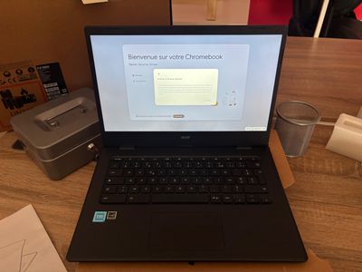 a laptop computer sitting on a desk with a cup of water