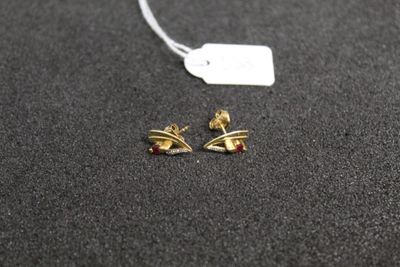une paire de boucles d'oreilles en or posées sur une surface noire, avec une étiquette de prix