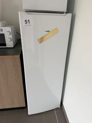 un réfrigérateur blanc sur lequel est collé un autocollant, à côté d'un micro-ondes