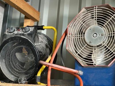un ventilateur posé sur une boîte bleue, à côté d'un tuyau jaune