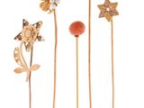 trois broches en forme de fleurs dorées et rouges sur fond blanc