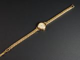 une image représentant une montre-bracelet en or posée sur une surface noire