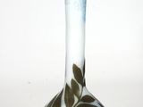 a white and blue vase with green leaves on it