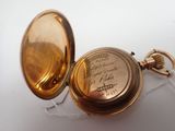 a gold pocket watch sitting on a white surface