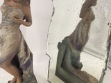 a statue of a woman that is standing in front of a mirror