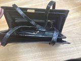 someone is holding a black purse with two pens and a pen in it