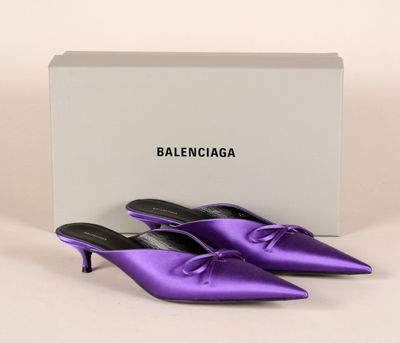 une paire de mules en satin violet avec une boîte blanche en arrière-plan