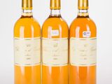 trois bouteilles de vin posées les unes à côté des autres sur une surface blanche