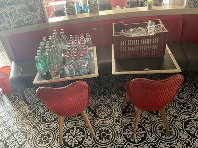 deux chaises rouges et une table sur laquelle sont posées des bouteilles d'eau