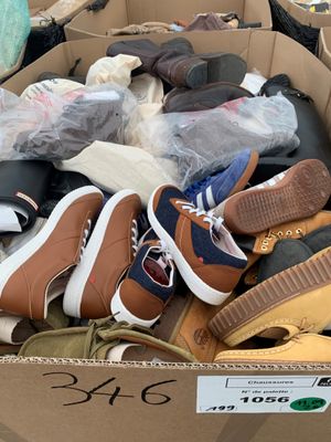 plusieurs paires de chaussures dans une boîte en carton posée sur le sol