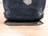 a black purse with a chain hanging from it on a table
