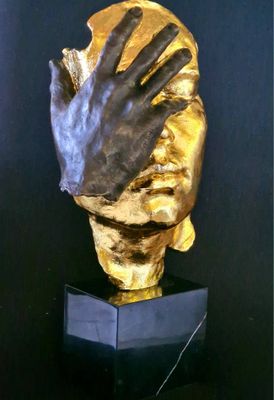 a gold sculpture of a hand holding a human hand