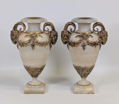 une paire de vases blancs et dorés posés sur une table blanche