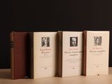 Trois livres sont alignés sur une table devant un fond noir.