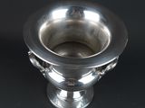 a silver vase that is sitting on a black surface