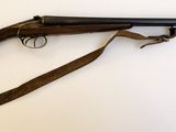 un fusil avec un canon en bois et une bretelle, posé sur une surface blanche