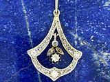 un pendentif en or et diamants posé sur une surface en marbre bleu