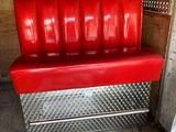 a red bench in a room with a newspaper on the floor