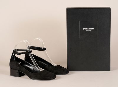 une paire de chaussures noires posée à côté d'une boîte sur une surface blanche