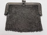 a black metal purse with chain around it on a white surface