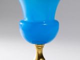 a blue vase on a gold stand on a white background