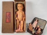 a small doll in a box next to a small doll in a suitcase