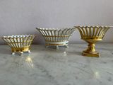 three gold and white bowls sitting on a marble counter top
