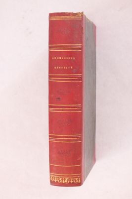 un vieux livre rouge posé sur une surface blanche
