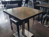 tables and chairs in a restaurant with a large painting on the wall