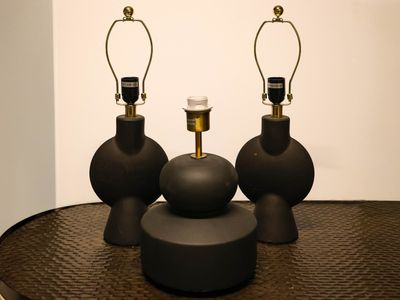 three black vases sitting on top of a table