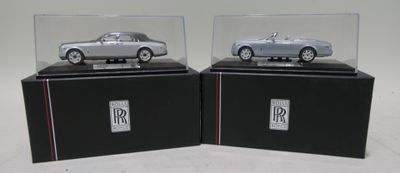 pair of silver model cars in display cases on black bases