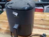 une friteuse à air chaud noire posée sur une table en bois