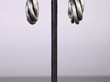 a close up of a pair of silver hoop earrings on a black stand